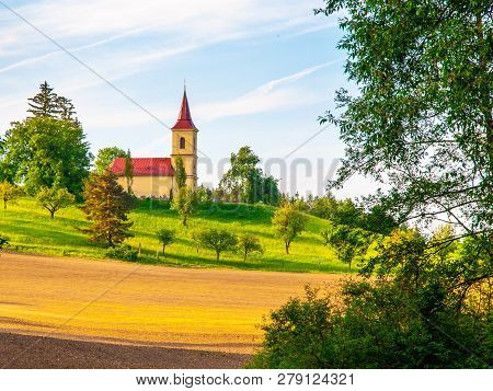Small Church In The Middle Of Lush Green Spring Landscape On Sunny Day. St. Peter And Pauls Church A