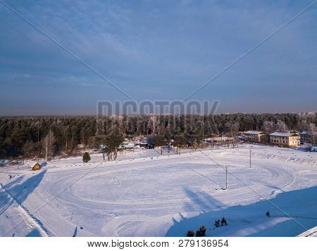 Helicopter Drone Shot. Aerial Photography Of Green Forest  And Stadium With Road, House In Cold Wint