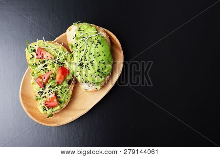 Two Healthy Toasts With Avocado, Micro Greens And Tomatoes On Wooden Plate. Vegetarian Breakfast Or 