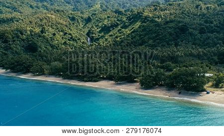 Aerial Drone Image Of A South Pacific Village On A Remote Island With Sandy Beach Shore And Lush Tro