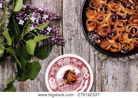 Homemade Mini Cherry Rolls In A Baking Form And One Roll On A Plate With Bouquet Of Lilac On Vintage