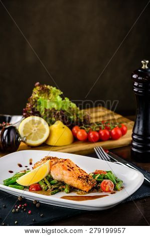 One Piece Of Baked Grillen Salmon Filet Pepper Lemon And Salt, With Vegetables Served On Black Stone