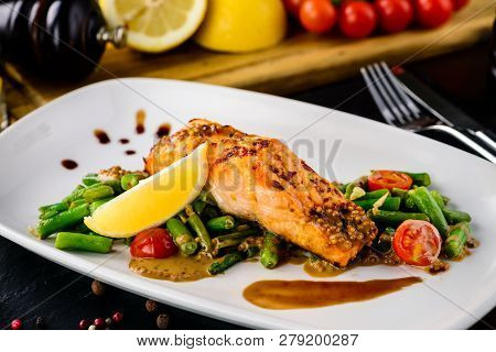 One Piece Of Baked Grillen Salmon Filet Pepper Lemon And Salt, With Vegetables Served On Black Stone