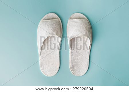 Pair Of White House Slippers On Seafoam Green Background. Top View Of Disposable Slippers In Bright 