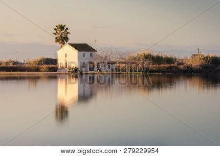Beautiful Landscape With Farmhouse In Albufera Lagoon, Reflection, Blue Sky And Yellow Sunlight In S