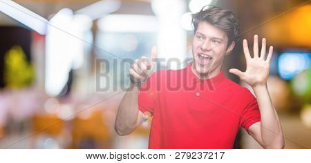 Young handsome man wearing red t-shirt over isolated background showing and pointing up with fingers number six while smiling confident and happy.