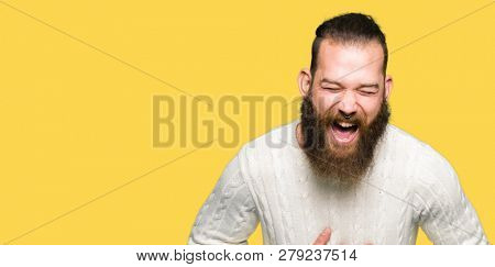 Young hipster man wearing winter sweater Smiling and laughing hard out loud because funny crazy joke. Happy expression.