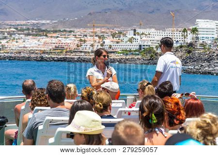 Costa Adeje, Tenerife, Canary Islands, Spain - July 26, 2018: Guide And Tourists On A Ship Against T