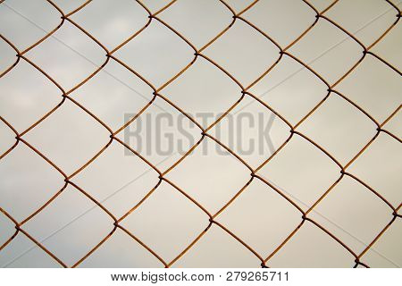 Rusty Abandoned Mesh Netting Against The Gray Sky.
