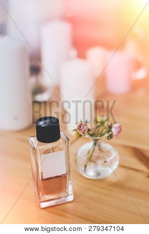 Bottle Of Perfume On Background Of Candles And Vase With Tiny Flowers, Selective Focus