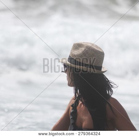 Beautiful Girl With Hat At The Sea Who Walking In The Water. The Sea In The Background. Sabaudia, La