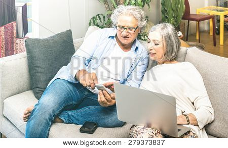 Senior Retired Couple Using Laptop Computer At Home On Sofa - Elderly And Technology Concept With Ma