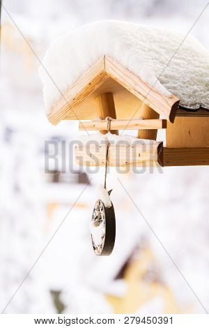 A Snow Covered Wooden Birdfeeder In Winter.