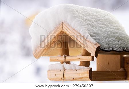 A Snow Covered Wooden Birdfeeder In Winter .
