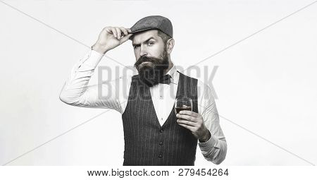 Degustation, Tasting. Man With Beard Holds Glass Of Brandy. Bearded Man Wearing Suit And Drinking Wh