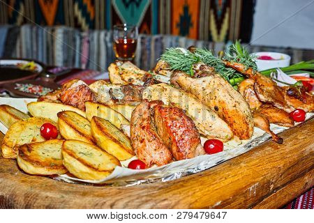 Wooden Board With Grilled Meats And Baked Potatoes With Dill.