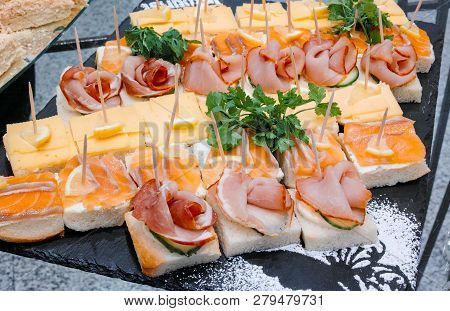 Buffet Plate With Canapes Of Salmon, Ham And Cheese, Decorated With Lemon Slices And Greens.