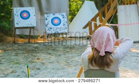 Medieval Female Archer Shooting Targets With Wooden Bow At Historical Festival. Archery And Medieval