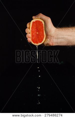 Drops Of Grapefruit Juice Fall From Fruit On Black Background