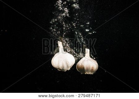 Fresh White Gurlics Fall In Water On Black Background