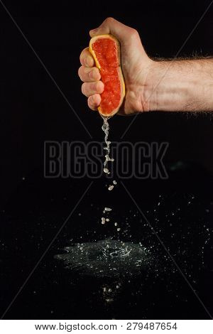 Grapefruit Juice Splashes From Half Of Fruit Held In Man's Hand