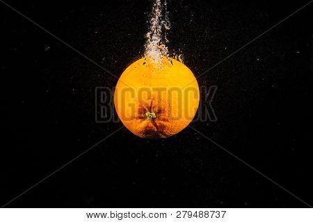 Juicy Orange Falls In Water On Black Background