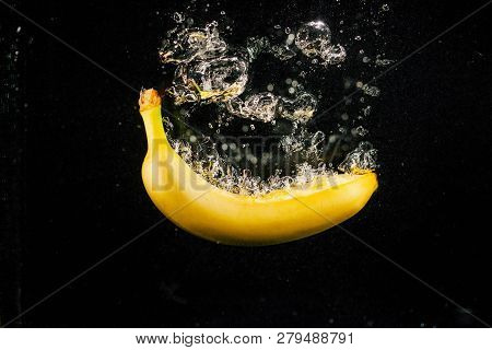 Large Bubbles Raise From Banana While It Falls In Water On Black Background