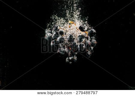 Large Bunch Of Black Grape Splashes Water Falling In Aquarium
