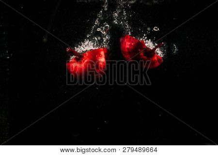 Pieces Of Red Onion Fall In Water On Black Background