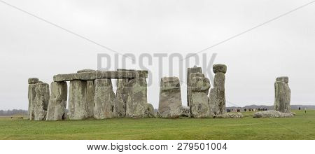 Amesbury, Great Britain - Dec 23, 2018: Tourists Watching The Stone Monument Stonehenge A Cloudy Day