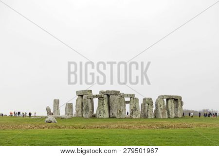 Amesbury, Great Britain - Dec 23, 2018: Tourists Watching The Stone Monument Stonehenge A Cloudy Day