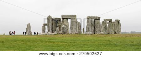 Amesbury, Great Britain - Dec 23, 2018: Tourists Watching The Stone Monument Stonehenge A Cloudy Day