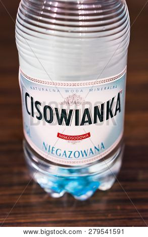 Poznan, Poland - November 17, 2018: Bottom Of A Polish Cisowianka Natural Water Bottle On A Wooden T