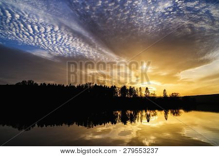 Sunset With Orange And Blue Dramatic Clouds And Its Reflection In Water Surface Of Lake In Vrbov, Sl