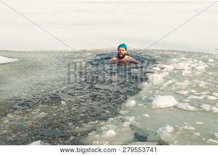 Bearded Man In Hat In Ice Hole Swimming