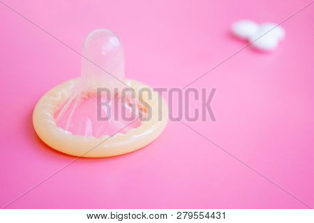 Opened Condom Close Up And Blurred Pills On Pink Background - Childfree And Sexual Health Concept.