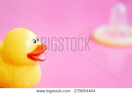 Childfree Contraception, Yellow Duckling Close Up And Blurred Opened Condom On Pink Background.