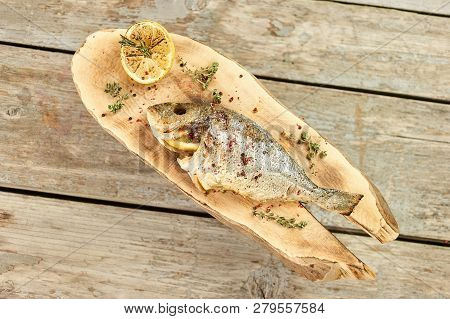 Cooked Fish Stuffed With Lemons, Down View. Prepareed Dorado Fish On Wooden Plate Stuffed With Lemon
