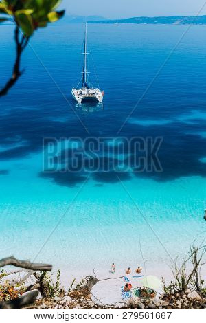 White Catamaran Yacht At Anchor On Clear Azure Surface With Dark Pattern In Calm Blue Lagoon. Unreco