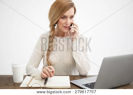 Modern Energetic Senior Woman Ceo In Elegant White Sweater Multitasking At Her Office Using Generic 