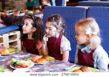 Kids In A Cafe Learning How To Cook Burgers.