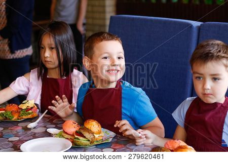 Kids In A Cafe Learning How To Cook Burgers