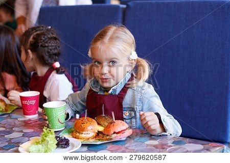 Kids In A Cafe Learning How To Cook Burgers