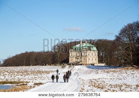 Klampenborg, Denmark - February 12, 2017: The Hunting Lodge And People Walking In The Snowy Deer Par