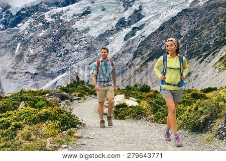 New Zealand tourists people tramping with backpacks on Mount Cook / Aoraki Hooker valley travel. Backpacking hikers hiking on Hooker Valley Track. Couple walking.