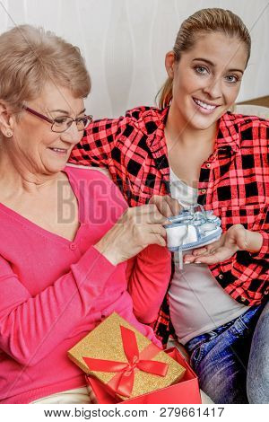 Granddaughter giving grangmother gift for her day or brithday. Celebration.