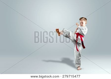 Creative Background, A Child In A White Kimono Makes A Kick, On A Light Background. The Concept Of M