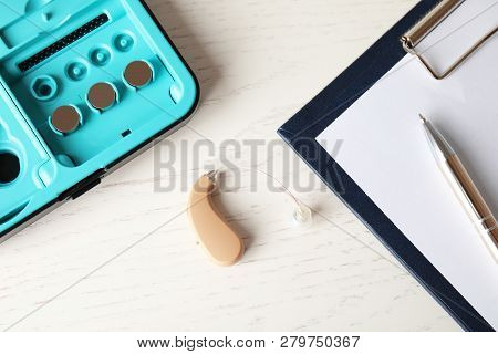 Hearing Aid And Case On White Wooden Table, Top View