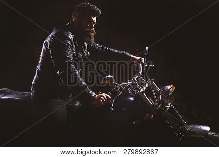 Man With Beard, Biker In Leather Jacket Sitting On Motor Bike In Darkness, Black Background. Night R