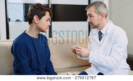 A Doctor Shows A Hearing Aid To A Hearing Impaired Guy.